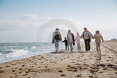 big multigenerational family walking together on beach Stock Photo