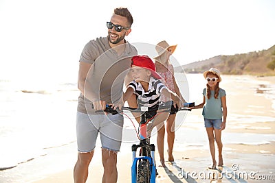 Happy family with bicycle on sandy beach near sea Stock Photo