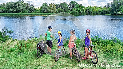 Family on bikes cycling outdoors, active parents and kids on bicycles, aerial top view of happy family with children near river Stock Photo