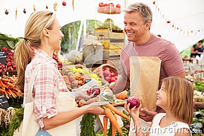 Family Buying Fresh Vegetables At Farmers Market Stall Stock Photo