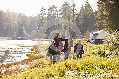Family on a camping trip walking near a lake looking away Stock Photo