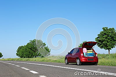 Family car with open trunk full of luggage on highway Stock Photo