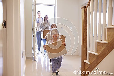 Family Carrying Boxes Into New Home On Moving Day Stock Photo