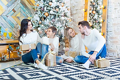 Family celebrating at home. father, mother and children on the background of the Christmas tree with presents sit on the Stock Photo