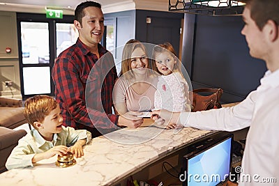 Family Checking In At Hotel Reception Desk Stock Photo