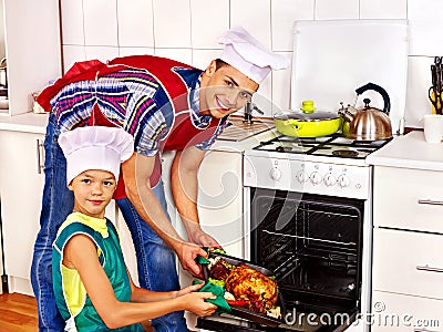 Family with child cooking chicken at kitchen. Stock Photo