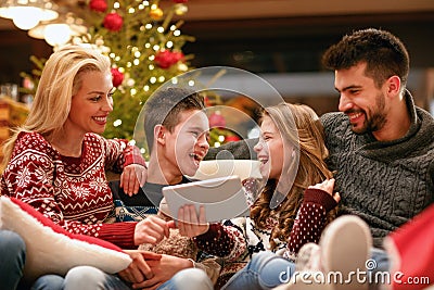 family, Christmas, x-mas, technology and people concept - watching funny video on digital tablet. Stock Photo