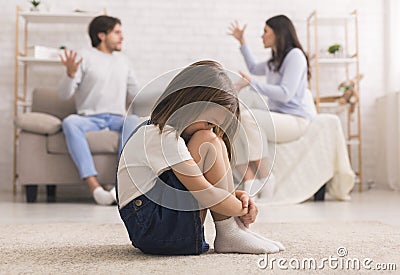 Family Conflict. Little girl crying after parents quarrel at home Stock Photo