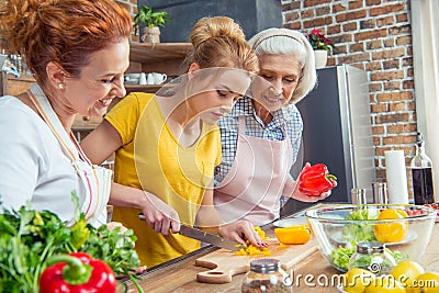 Happy three-generation family cooking together vegetable salad Stock Photo