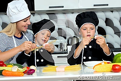 A family of cooks.Mother and children prepares spaghetti in kitchen. Stock Photo