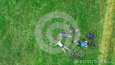 Family cycling on bikes outdoors aerial view from above, happy active parents with child have fun and relax on grass Stock Photo