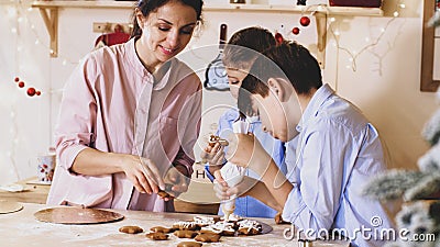 Family is decorating a Christmas cookies with pastry bag at home kitchen. Stock Photo