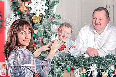 Family decorating a Christmas tree with boubles in the living-room Stock Photo