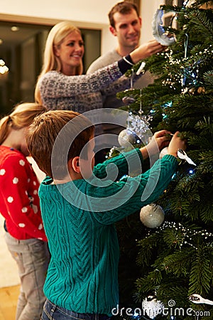 Family Decorating Christmas Tree At Home Together Stock Photo