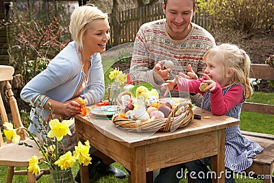 Family Decorating Easter Eggs On Table Outdoors Stock Photo