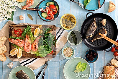 Family dinner table with shrimp, fish grilled, salad, different Stock Photo