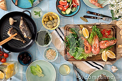 Family dinner table with shrimp, fish grilled, salad, snacks, le Stock Photo