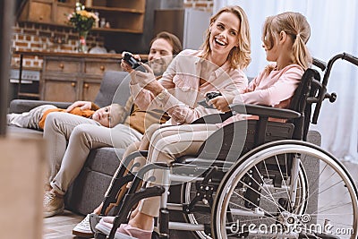 family with disabled child in wheelchair playing with joysticks together Stock Photo