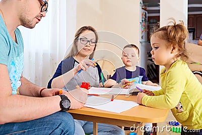 The family draws pencils at a table in room Stock Photo