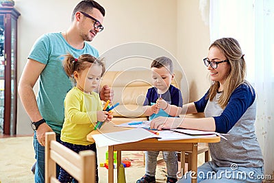The family draws pencils at a table in room Stock Photo