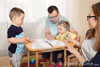 The family draws pencils at a table in room Stock Photo