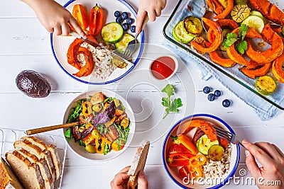 Family eating a healthy vegetarian food. Vegan lunch table top view, plant based diet. Baked vegetables, fresh salad, berries, Stock Photo