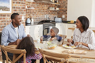 Family Eating Meal In Open Plan Kitchen Together Stock Photo