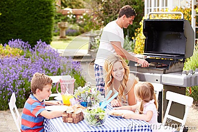 Family Enjoying Outdoor Barbeque In Garden Stock Photo