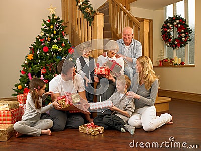 Family exchanging gifts in front of Christmas tree Stock Photo