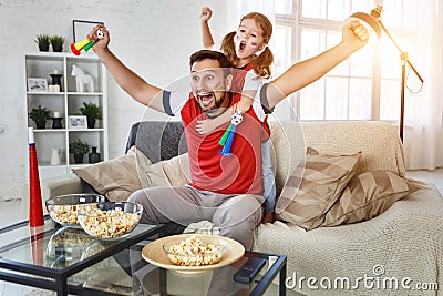 Family of fans watching a football match on TV at home Stock Photo