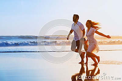 Family - father, mother, baby run on sunset beach Stock Photo