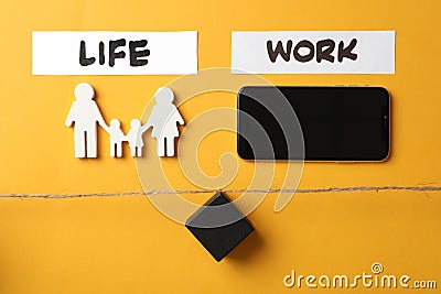 Family figures, smartphone and black cube on yellow wooden table, flat lay. Life work balance concept Stock Photo