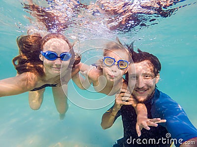 Family fitness - mother, father, baby son learn to swim together, dive underwater with fun in pool Active parent lifestyle, people Stock Photo