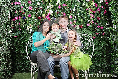 Family of four with bunch of flowers sit on bench Stock Photo