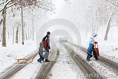 Family of four carefully crossing the street covered with snow and mud Editorial Stock Photo