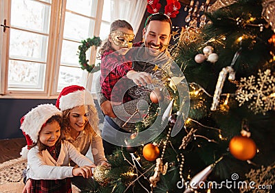 Family of four decorating a Christmas tree Stock Photo