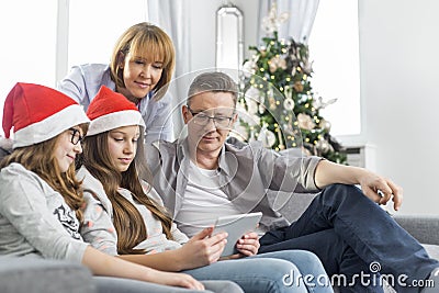 Family of four using digital tablet at home during Christmas Stock Photo