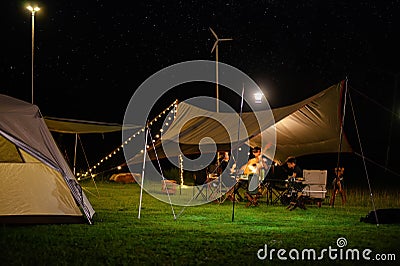 Family and friend vacation camp relax, Outdoor camping tent with tarp or flysheet on grass courtyard and warm night light under Stock Photo