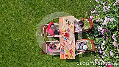 Family and friends eating together outdoors on summer garden party. Aerial view of table with food and drinks from above Stock Photo