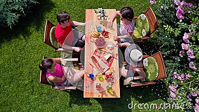 Family and friends eating together outdoors on summer garden party. Aerial view of table with food and drinks from above Stock Photo