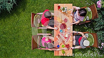 Family and friends eating together outdoors on summer garden party. Aerial view of table with food and drinks from above Stock Photo