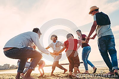 Family friends having fun on the beach at sunset - Fathers, mothers, children and uncles playing together - Focus on bodies - Love Stock Photo