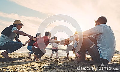 Family friends having fun on the beach at sunset - Fathers, mothers, children and uncles playing together - Love, relationship, Stock Photo