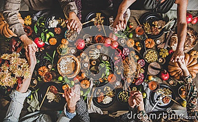 Family or friends praying holding hands at Thanksgiving celebration table Stock Photo