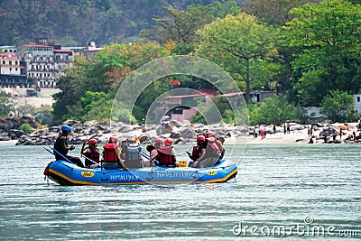 family friends sitting in raft enjoying adventure sports while crossing in front of ghat and temple on the banks of the Editorial Stock Photo