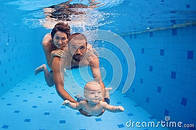 Family fun in swimming pool - mother, father, baby dive underwater Stock Photo