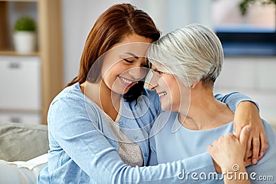 Senior mother with adult daughter hugging at home Stock Photo