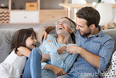 Family have fun daughter and daddy tickling mother Stock Photo