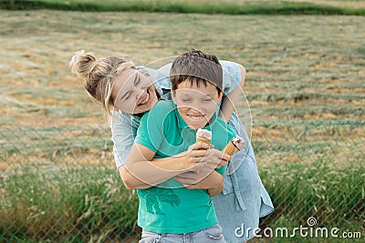 Family is having fun on the background of green grass, eating ice cream and laughing. Parent-teen relationship concept Stock Photo