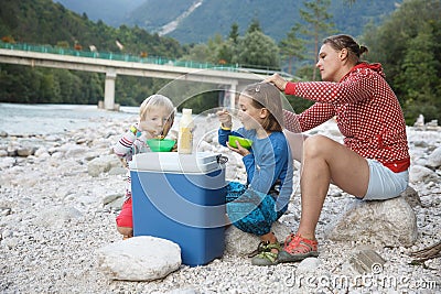 Family having a picnic in nature out of a cool box, sitting on the river bank Stock Photo